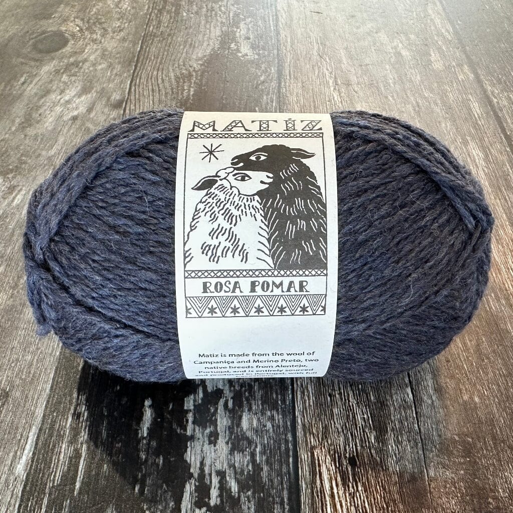 Ball of dark blue yarn with a label on a wooden surface