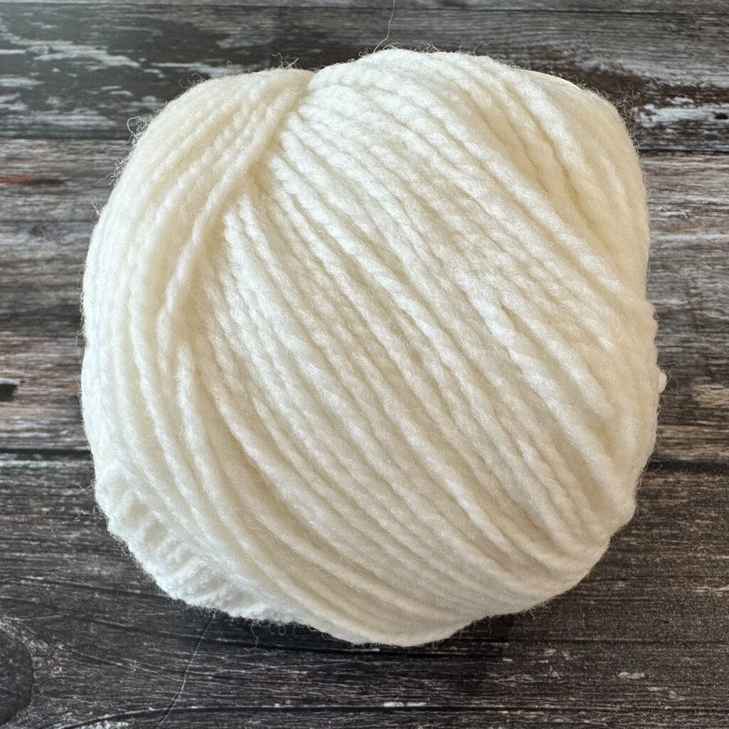 Ball of white yarn on a wooden surface