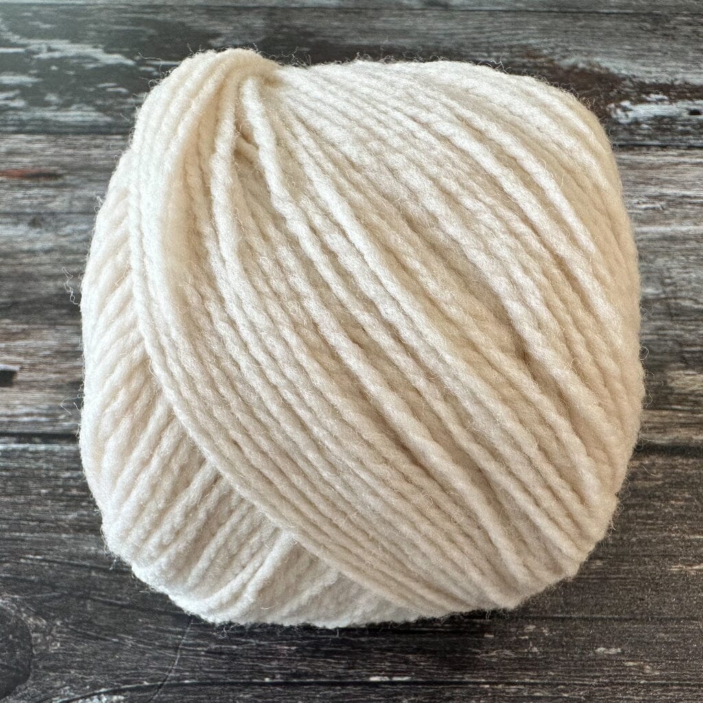 Ball of cream-colored yarn on a wooden surface
