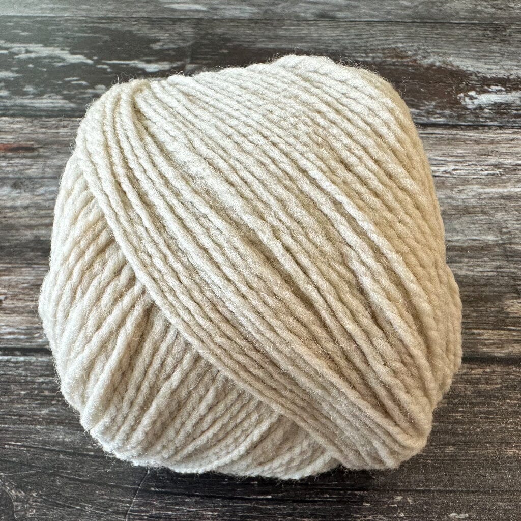 Ball of beige yarn on a wooden surface