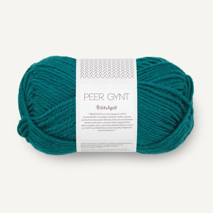 A skein of teal Peer Gynt  yarn with a white paper label, photographed on a clean, light off-white background.