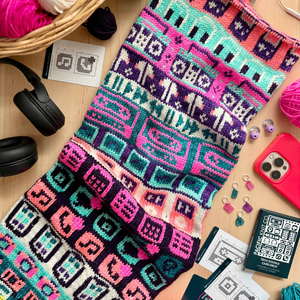 Colorful knitted pattern on a wooden surface with yarn and tools.