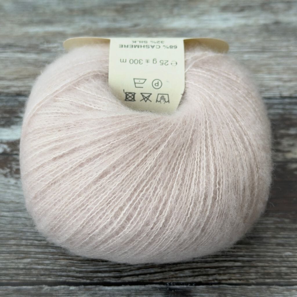 Ball of pink  yarn with a label on a wooden surface