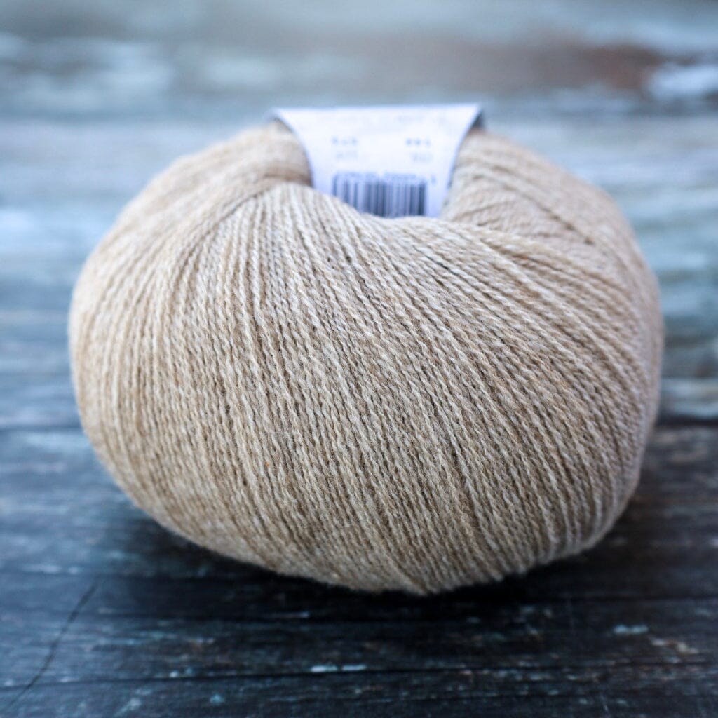 A ball of light beige yarn resting on a dark, weathered wooden surface.