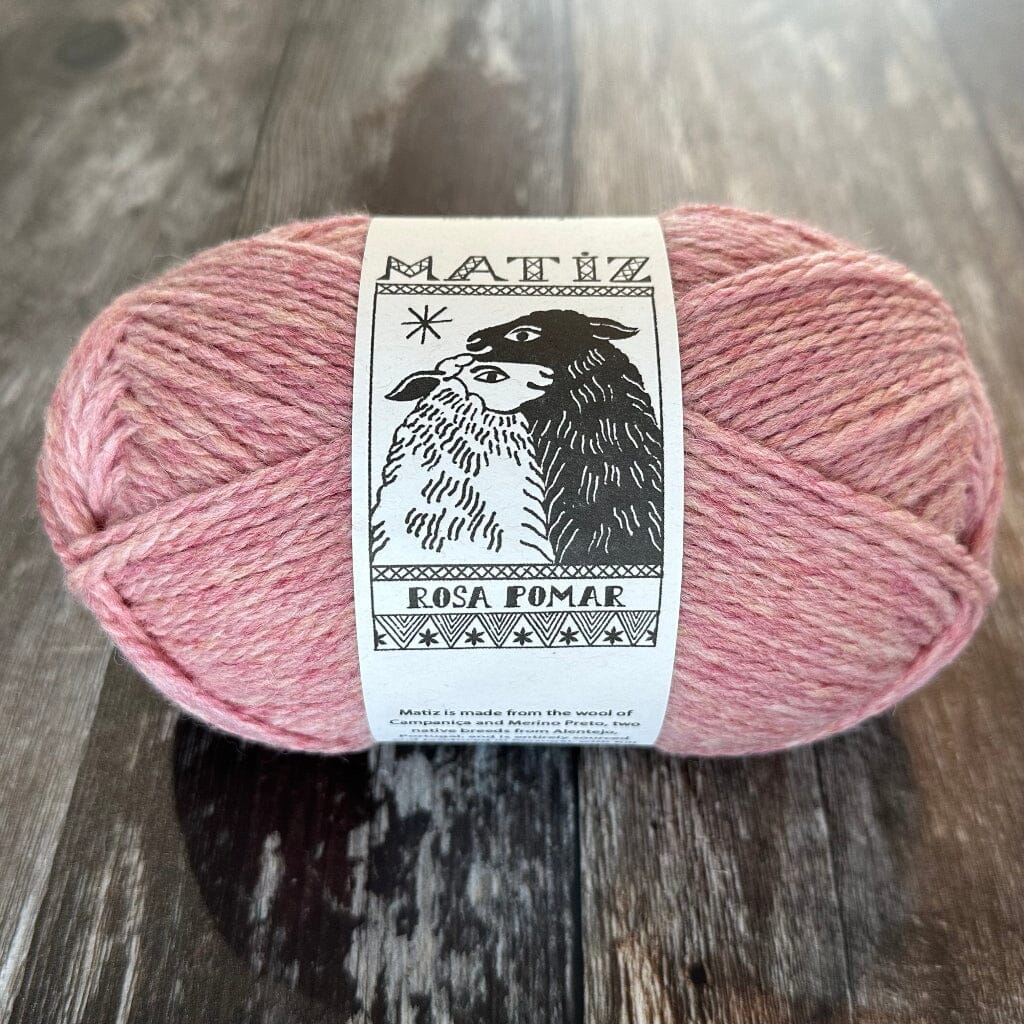 Pink yarn ball with a label on a wooden surface