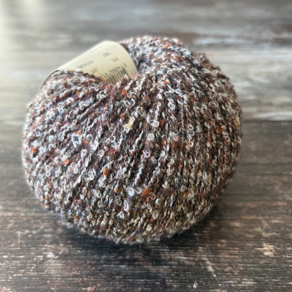 brown boucle cotton yarn on wooden surface