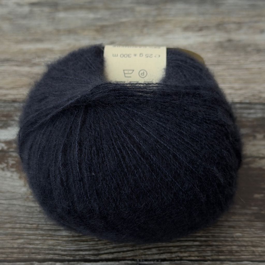 Dark blue skein of yarn with a label on a wooden surface