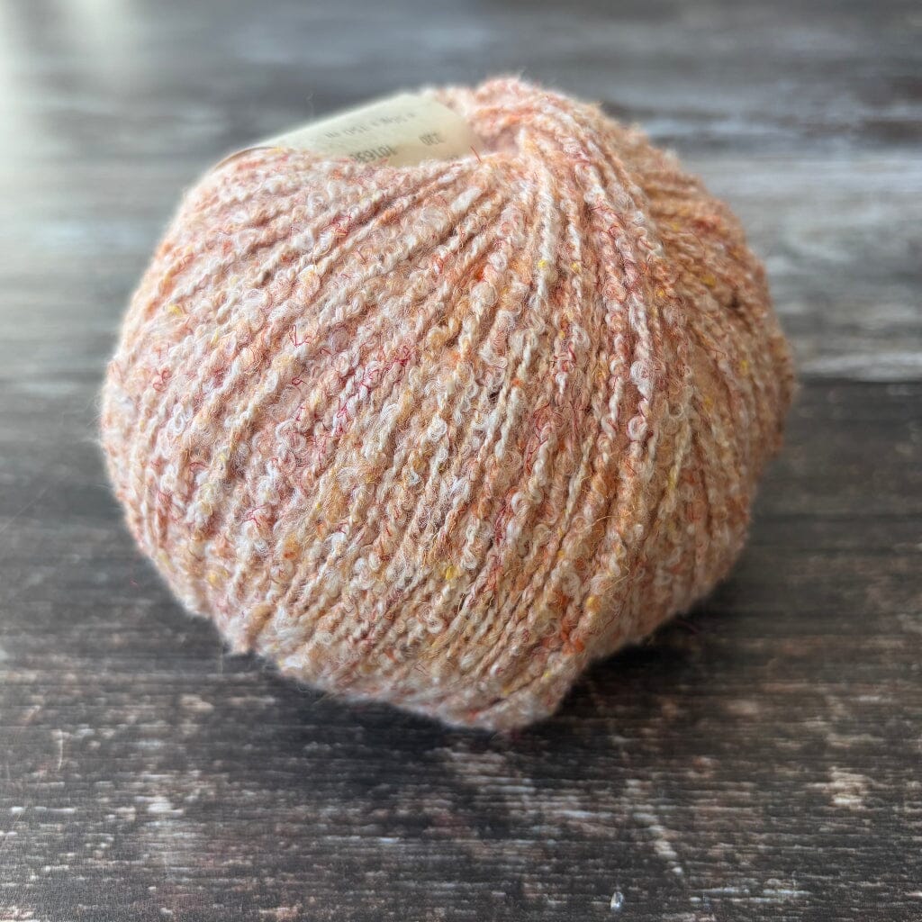peach boucle cotton yarn on wooden surface