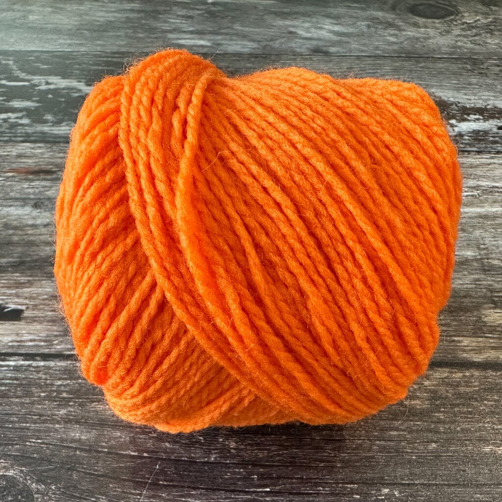 Orange yarn ball on a wooden surface