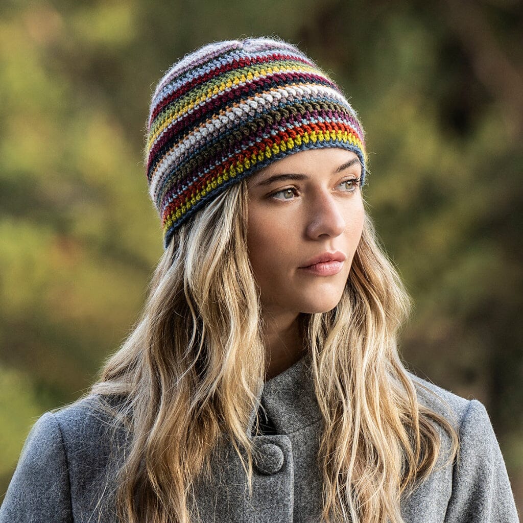 Woman wearing a colorful crocheted striped beanie and gray coat outdoors