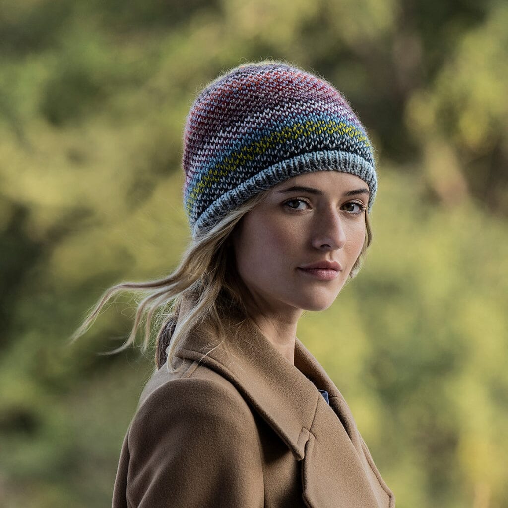 Woman wearing a colourful fair isle knited hat and brown coat in a natural setting