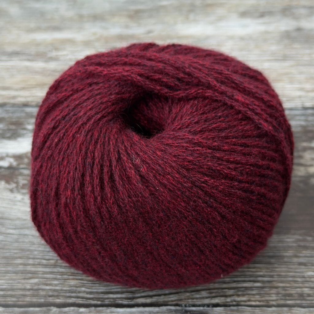 Ball of dark red yarn on a wooden surface
