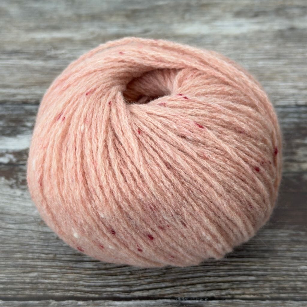 Ball of pink yarn on a wooden surface