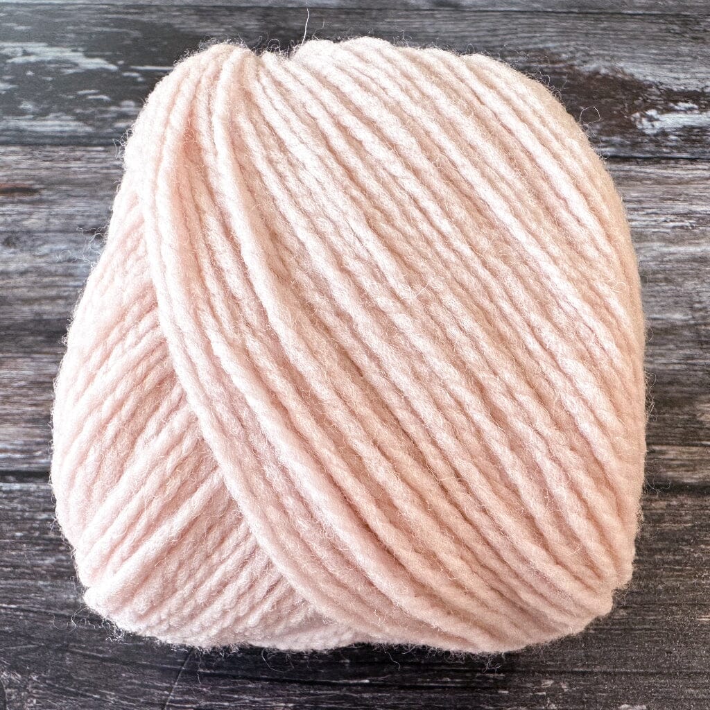 Ball of light pink yarn on a wooden surface