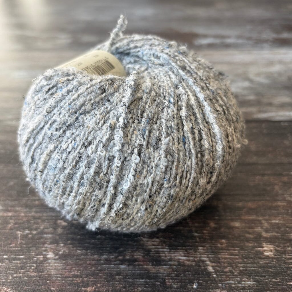 grey boucle cotton yarn on wooden surface