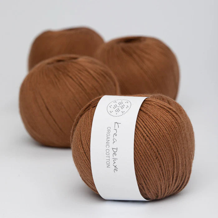 Three balls of brown yarn with a visible label on a light gray background