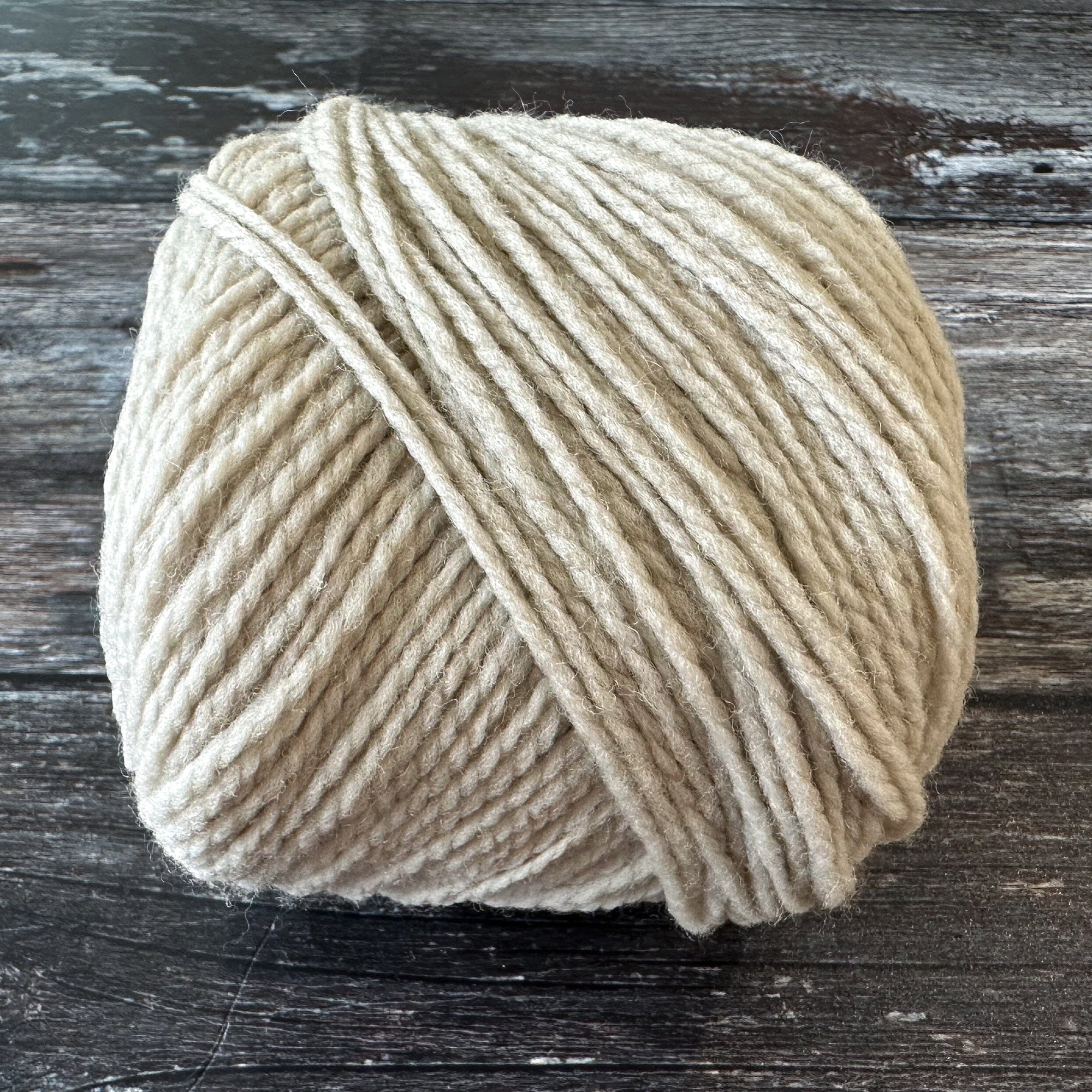 Ball of beige yarn on a wooden surface