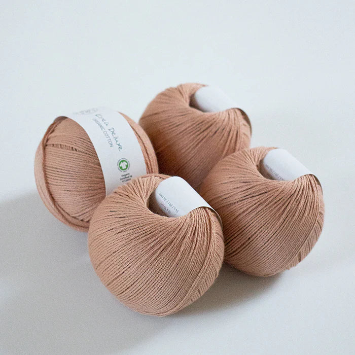 Four skeins of peach-colored yarn on a white background