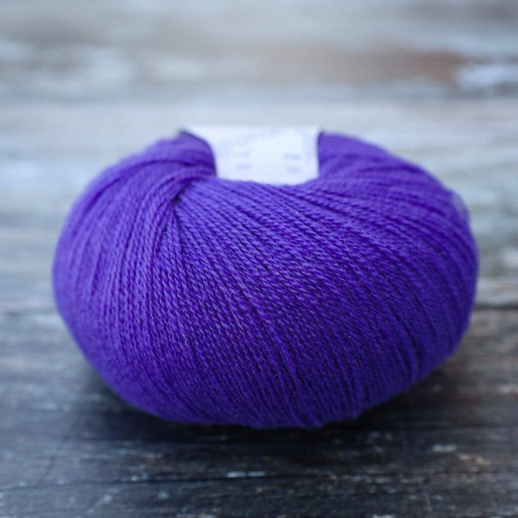 A ball of vibrant purple yarn resting on a rustic, weathered wooden surface.