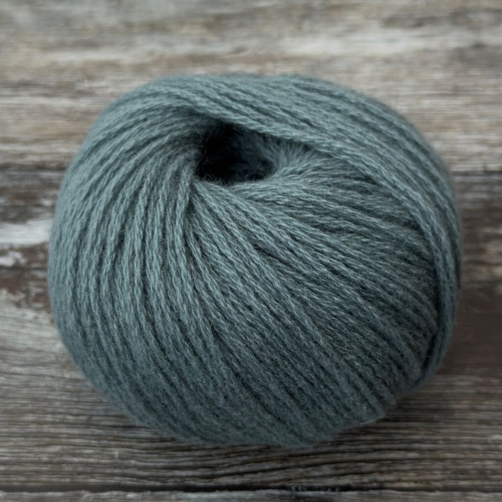 Ball of dark gray yarn on a wooden surface