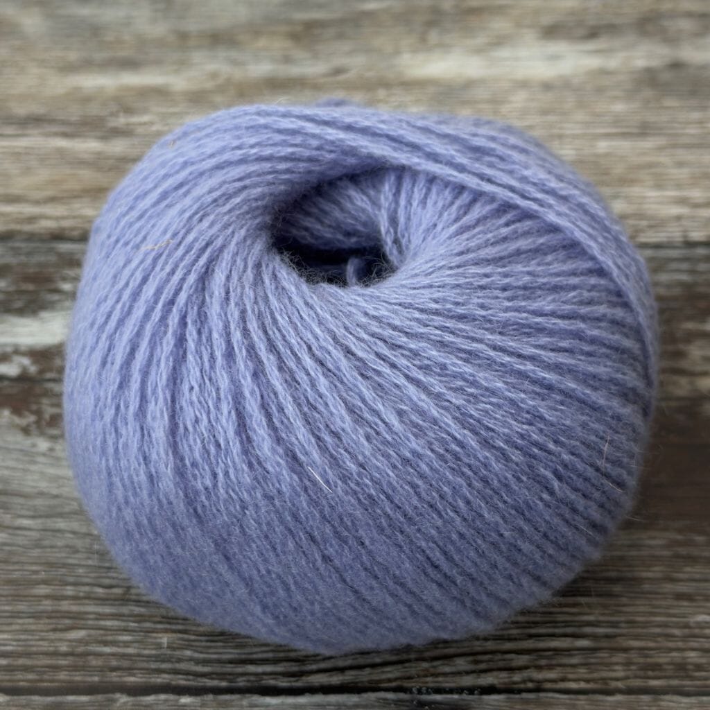 Ball of light purple yarn on a wooden surface