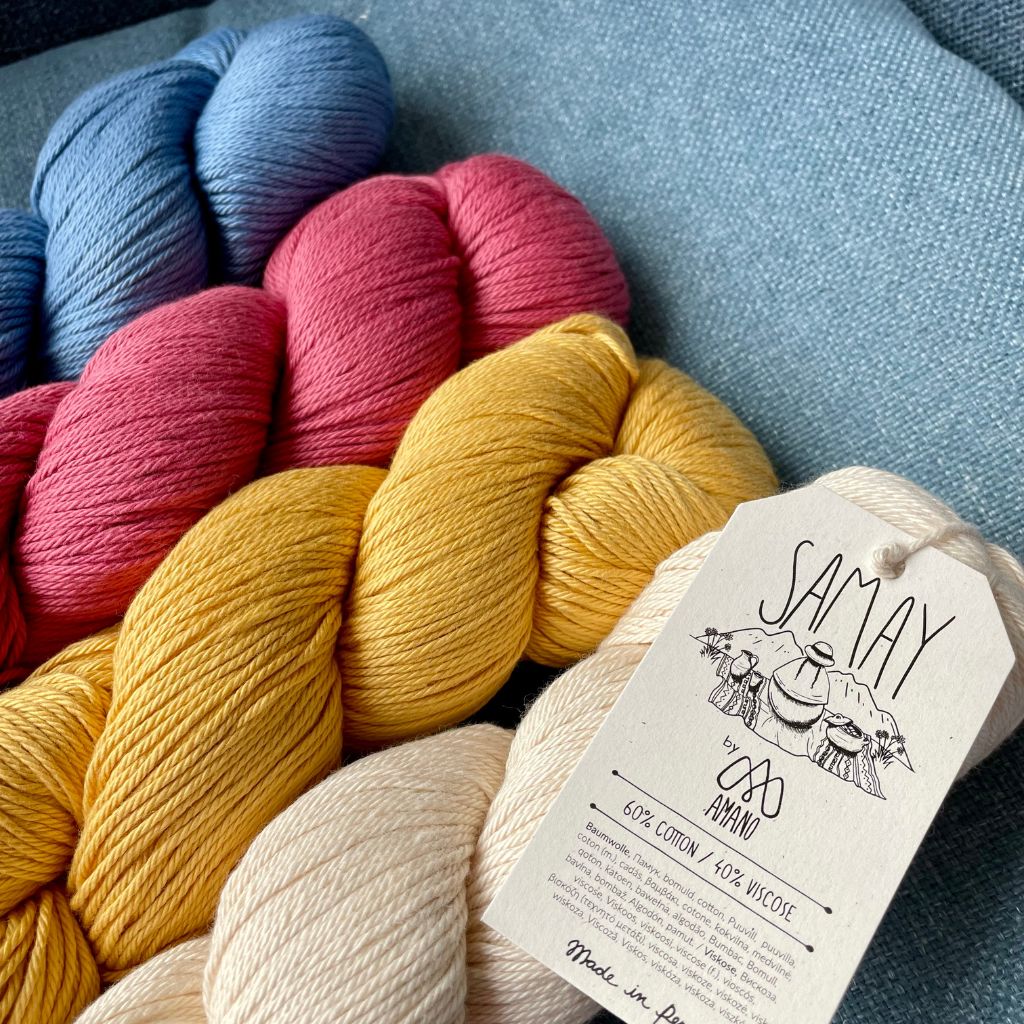 Bundles of yarn in various colors including blue, red, yellow, and beige, with a label that reads &#39;Samay&#39; and indicates the yarn is made from cotton and bamboo.