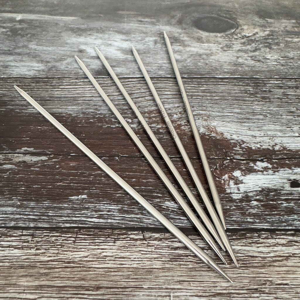 Five metal needles on a wooden surface
