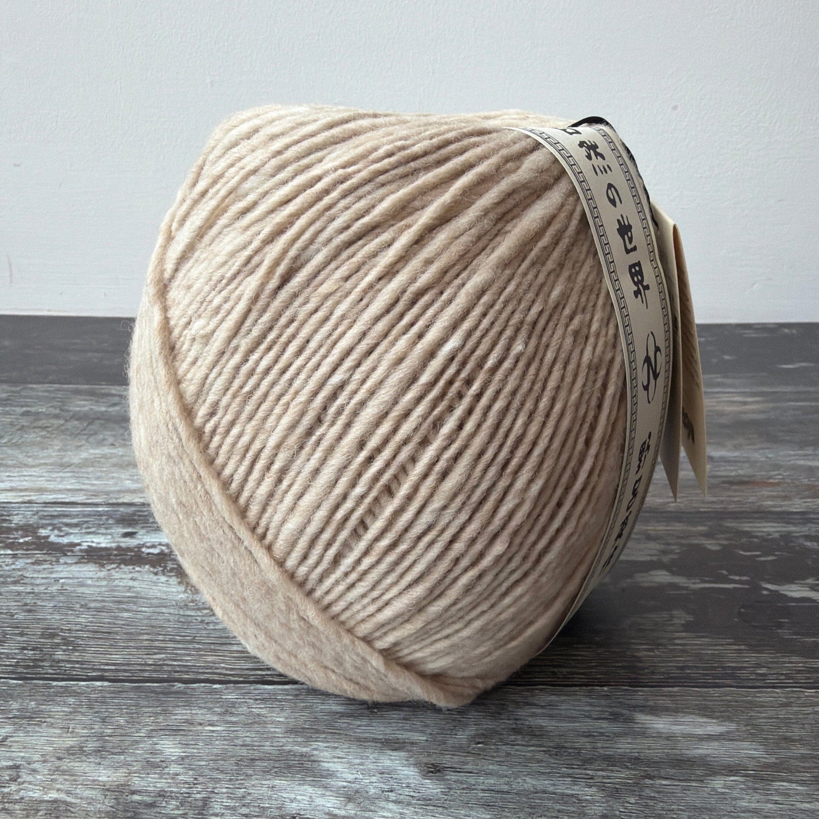 Three skeins of brown yarn with labels on a yellow surface