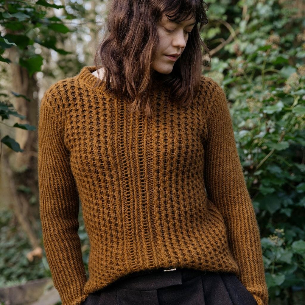 Woman wearing a brown knitted sweater standing in a forest setting