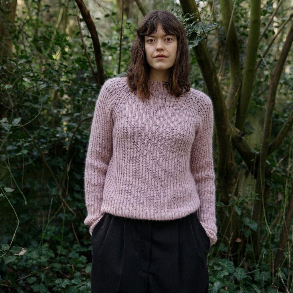 Woman wearing a pink knitted sweater standing in a forest