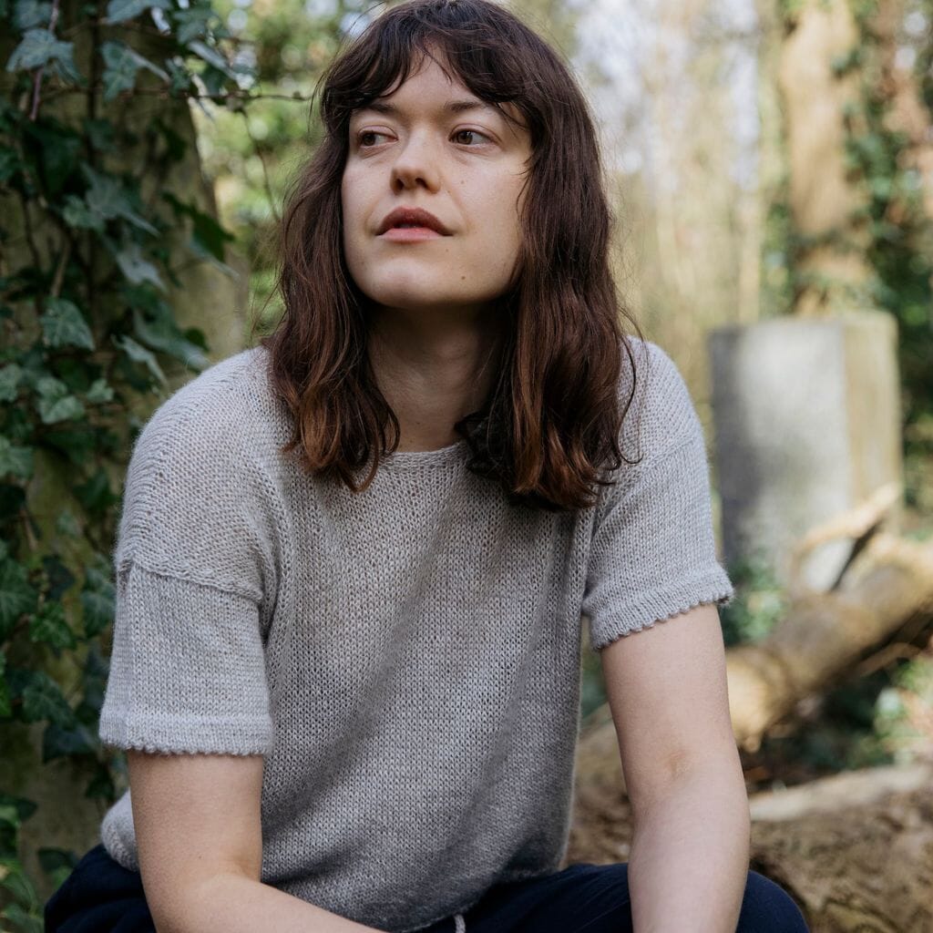 Woman sitting outdoors with greenery in the background