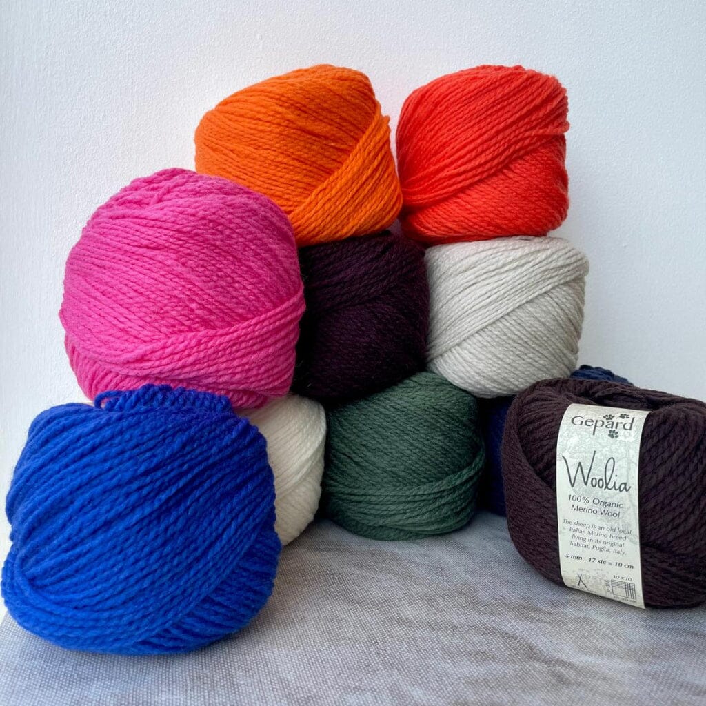 Assorted colorful yarn balls on a textured surface with a white background