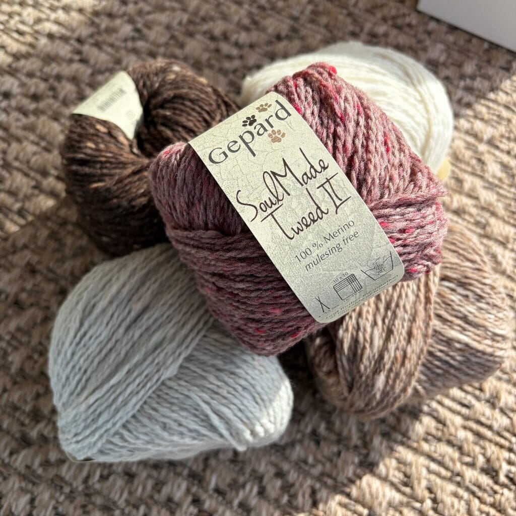 5 balls of tweed yarn in a pile, label says 'gepard soulmade tweed II' on woven carpet