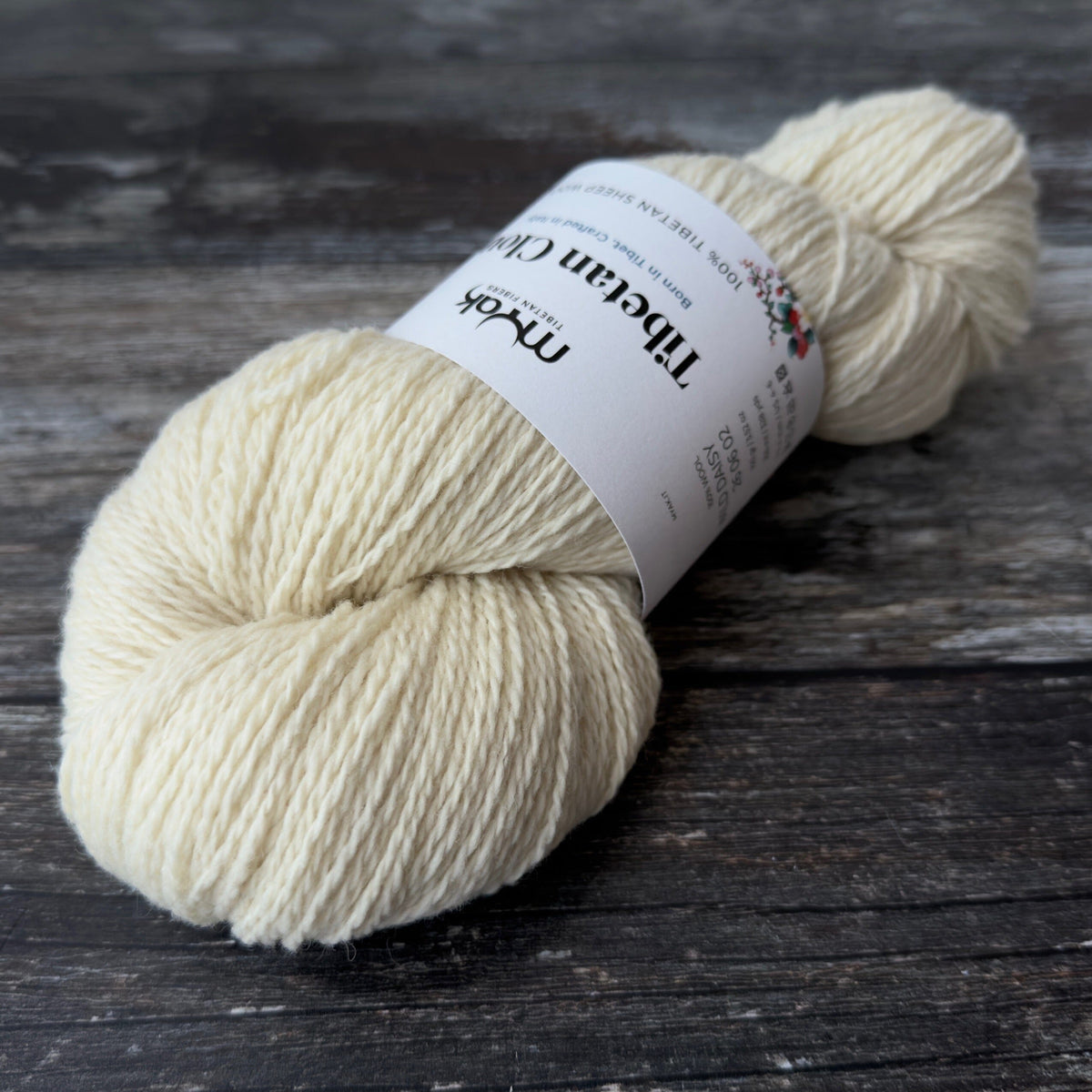 Ball of cream-coloured yarn with a label on a wooden surface