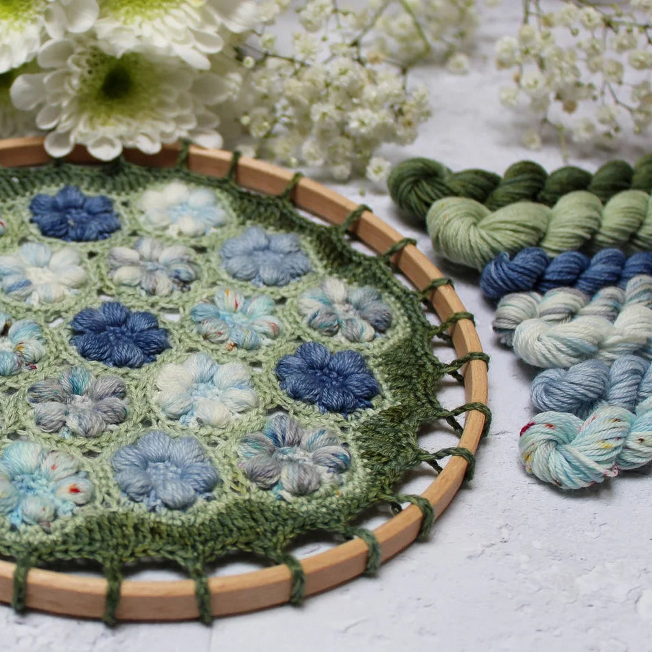 Handcrafted crochet item with yarn and flowers on a light surface