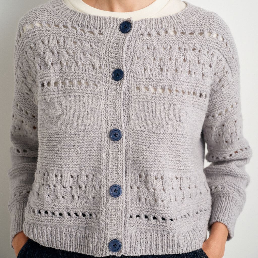 Gray knitted cardigan with blue buttons on a plain background
