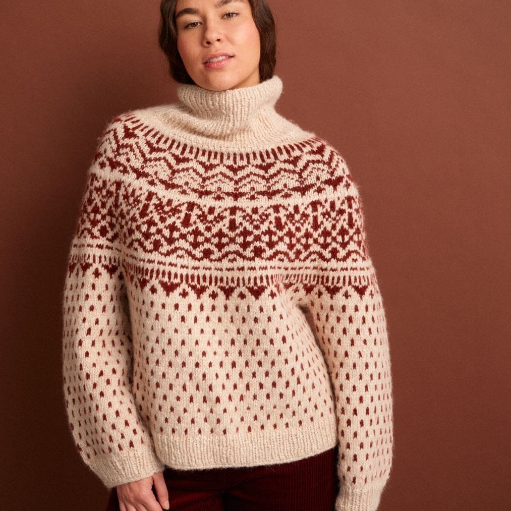 Person wearing a patterned sweater against a brown background