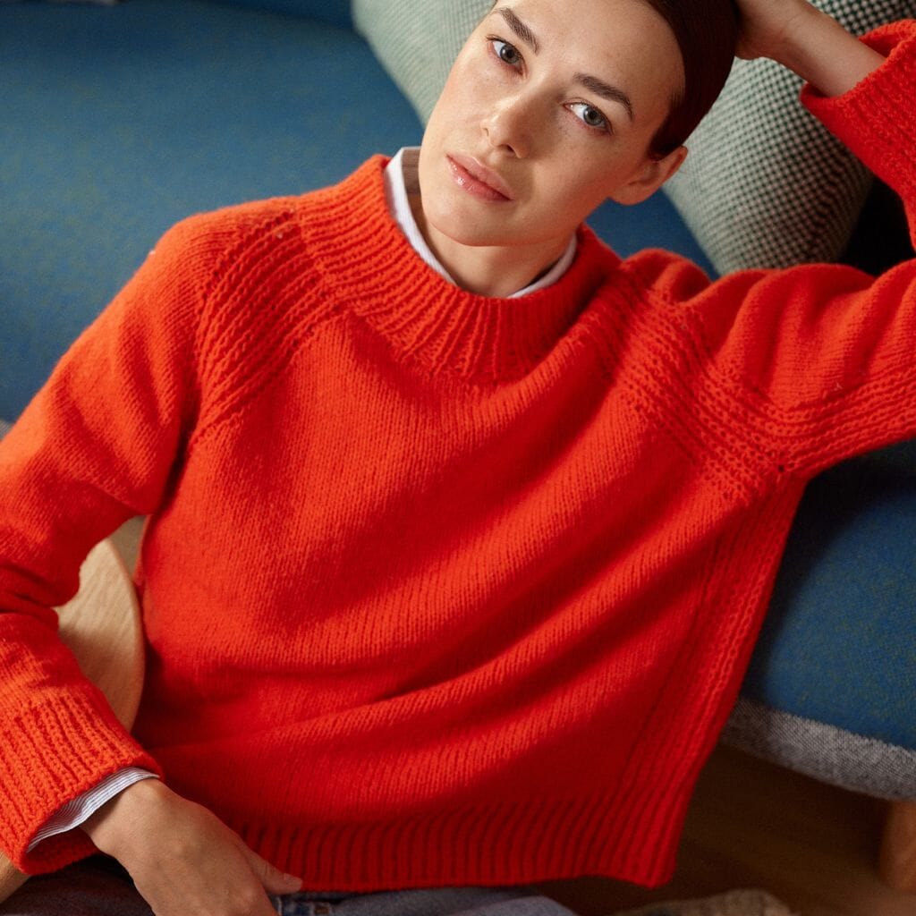Person wearing a red sweater sitting on a couch