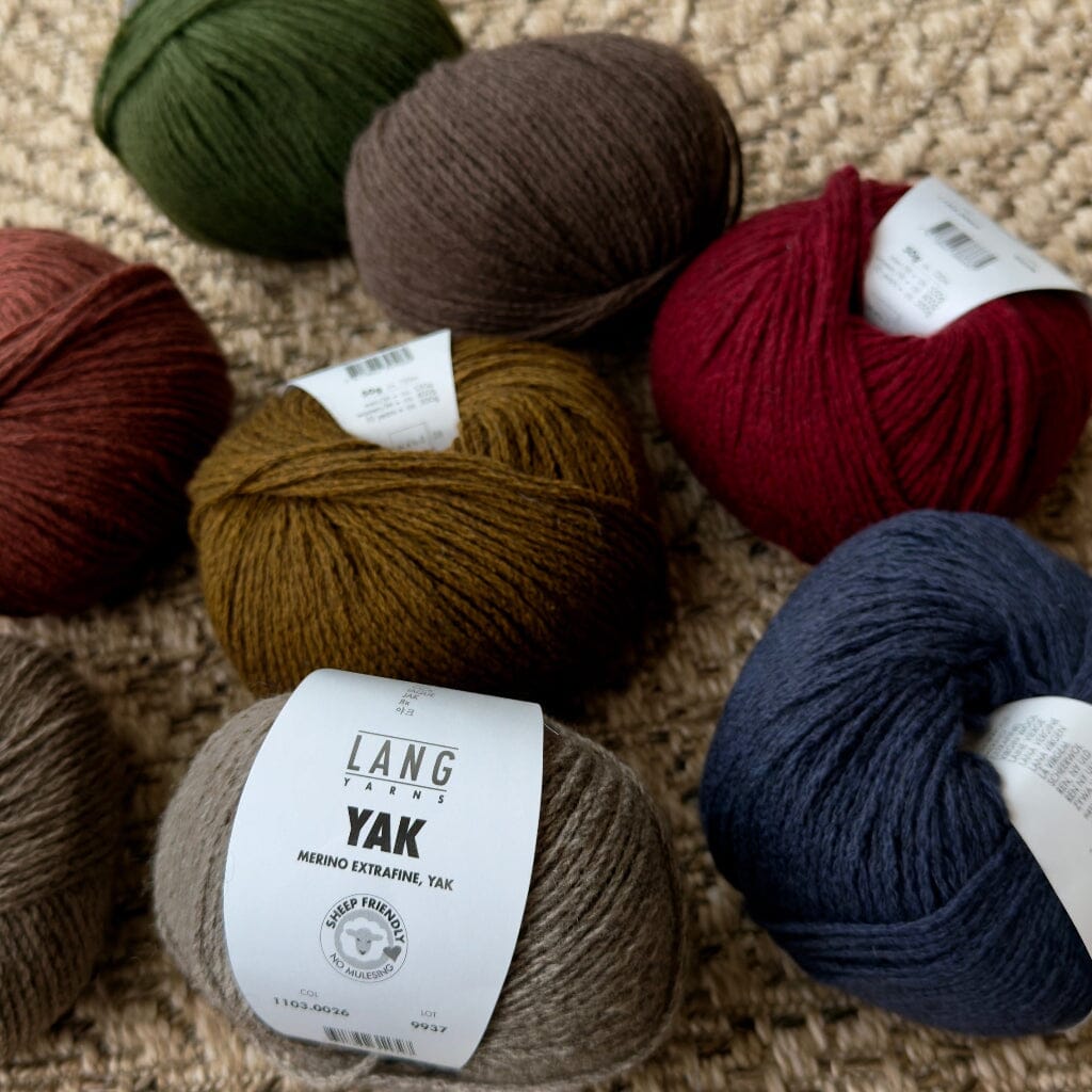 Assorted balls of yarn in various colors on a textured surface