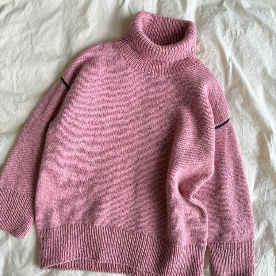 Pink sweater on a white textured surface