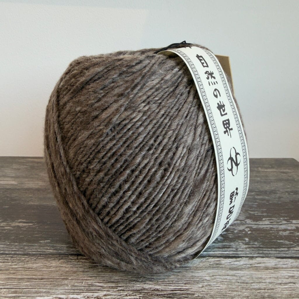 Ball of brown yarn with a label on a wooden surface