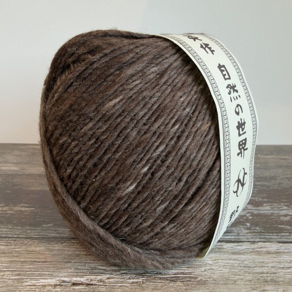 Ball of brown yarn with a label on a wooden surface