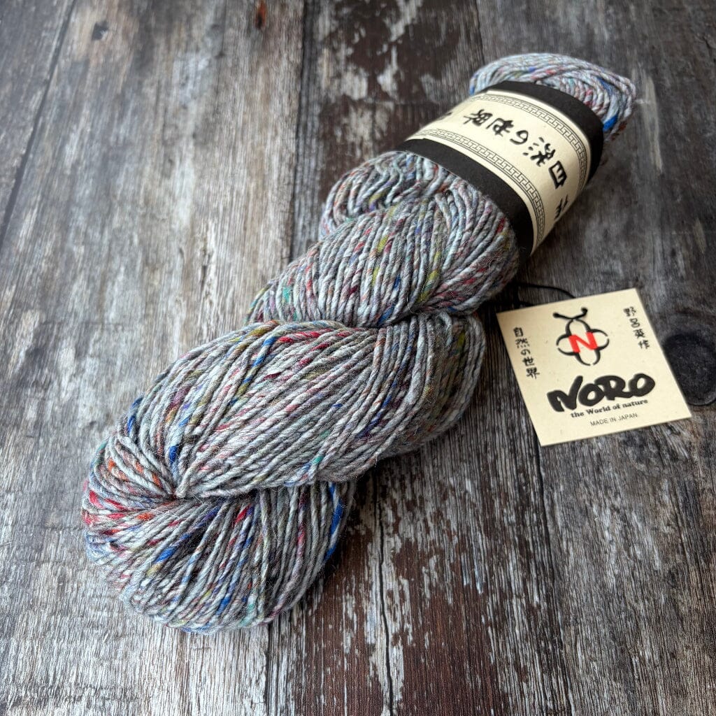 Multicolored skein of yarn with a Noro label on a wooden surface