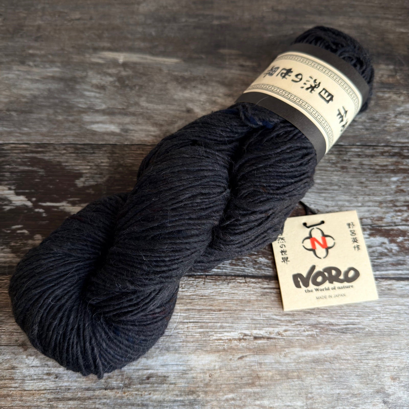 Dark skein of yarn with a Noro label on a wooden surface