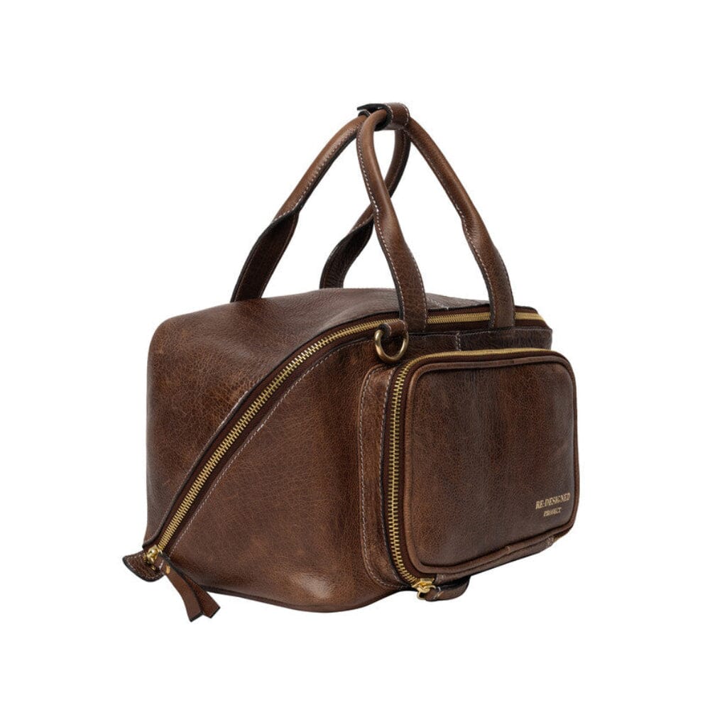 A brown leather knitting bag with gold-tone zippers and handles, shown from a three-quarter angle on a solid white background.