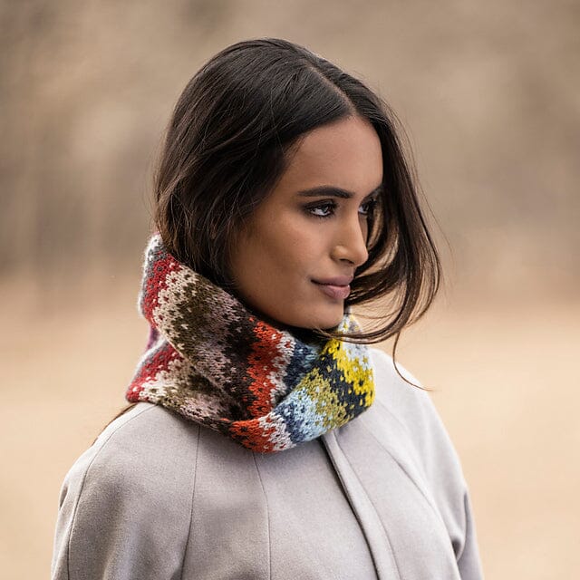 Woman wearing a colourful knitted scarf against a blurred natural background