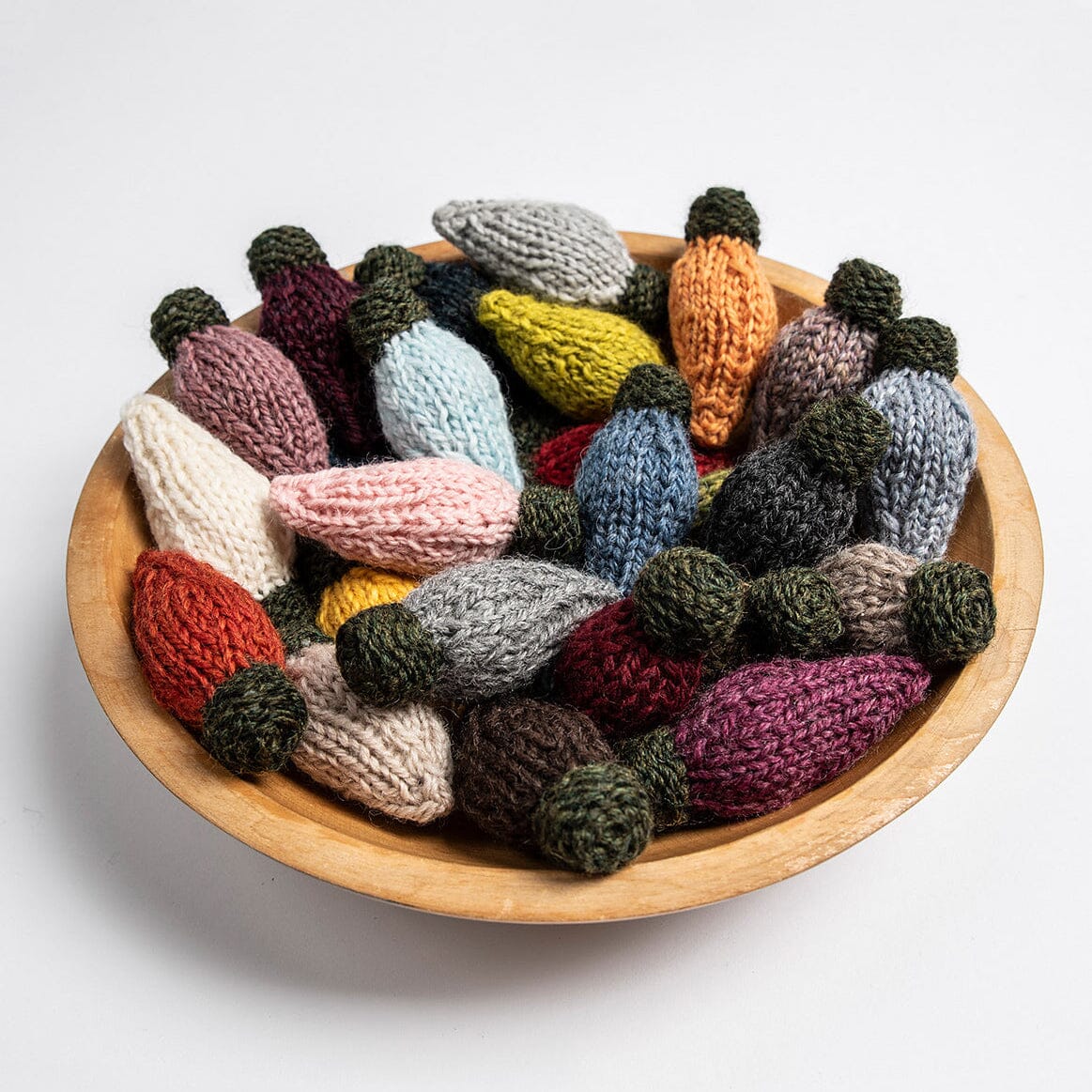 Wooden bowl filled with colourful knitted lights on a white background