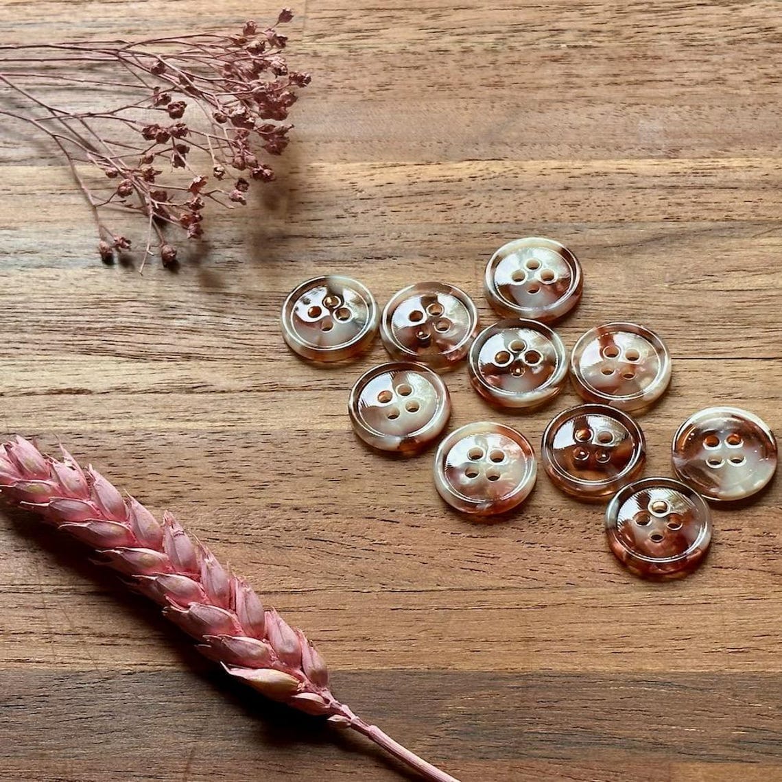 Set of round buttons on a wooden surface with dried flowers.