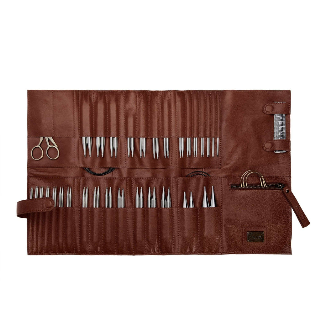 Brown leather needle case with sewing tools on a white background