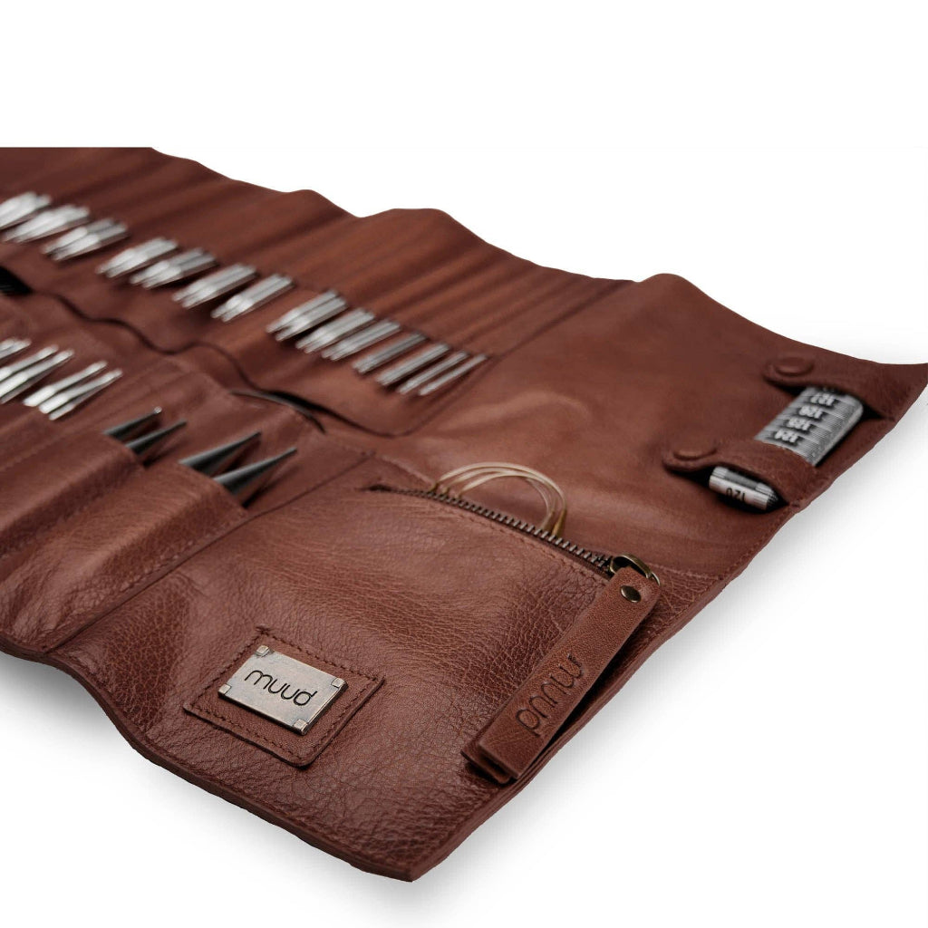 Brown leather tool roll with knitting needles on a white background